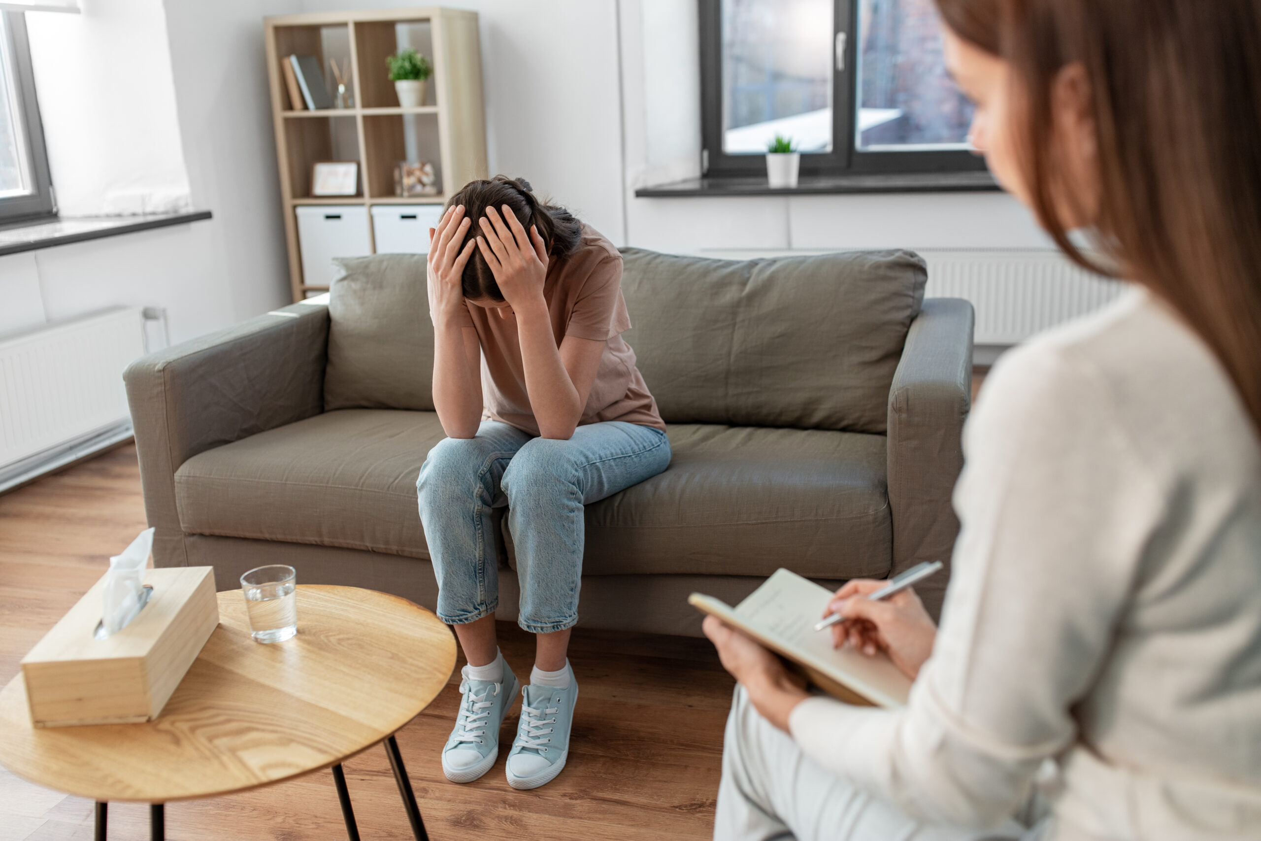 psychology, mental health and people concept - stressed young woman patient and psychologist at psychotherapy session